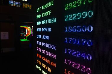 Colorful illuminated arcade scoreboard displaying high scores in a vibrant gaming ambiance.